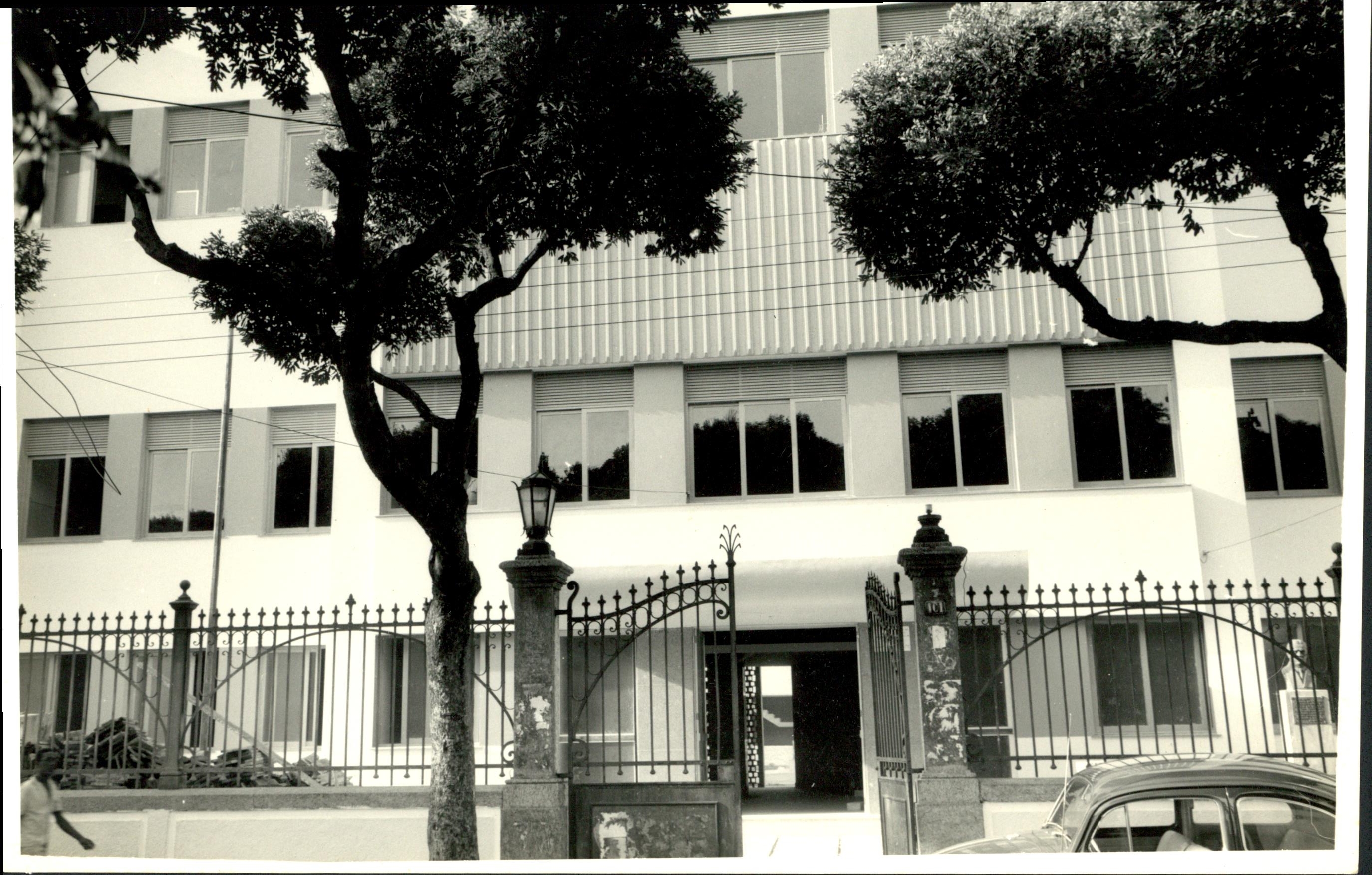 Prédio do Instituto Biomédico. Fachada de arquitetura moderna, entre 2 árvores na calçada o portão de entrada aberto, à Rua Prof. Hernani Pires de Mello, (antiga Rua Visconde Moraes) década de 198?